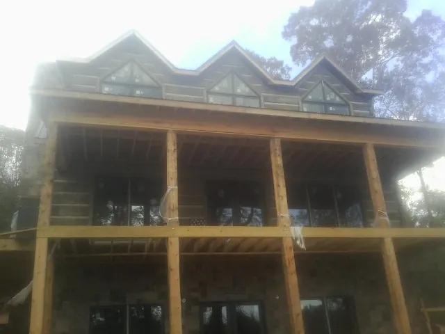 Dormers and porch framing on a large log home under construction — Roof Coating work by our crew in Liverpool