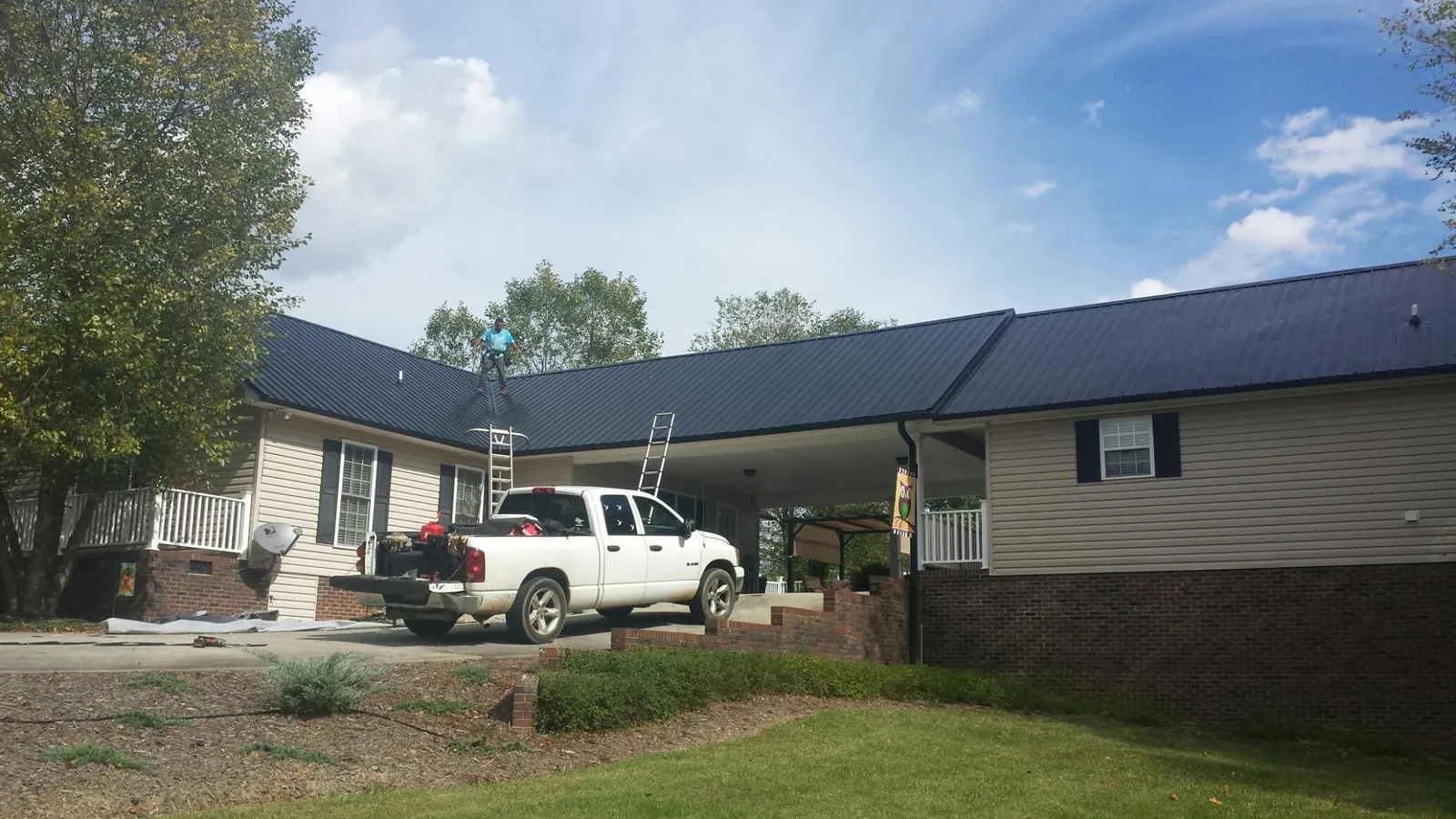 Black metal roof over a home and attached breezeway with ladders set in Liverpool
