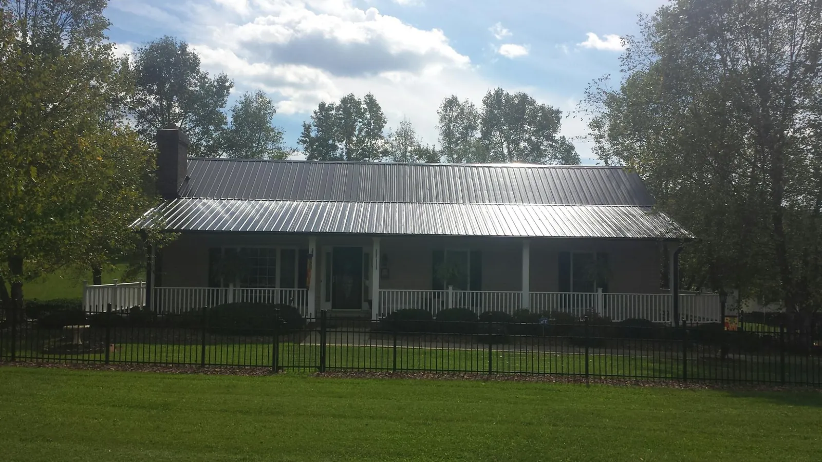 Gray metal roof on a brick ranch with a full width front porch — Gutter Guard Installation work by our crew in Liverpool